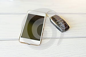 Smart phones with modern car key on wooden table