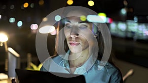 Smart pretty business woman taking a break while cheaking her digital tablet standing in the office at night