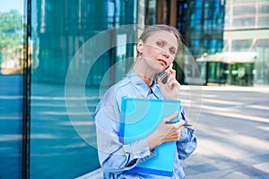 Smart professional caucasian business woman uses mobile phone in city outdoors