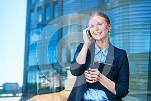 Smart professional caucasian business woman uses mobile phone in city outdoors