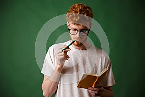 Smart readhead bearded student in glasses reading the notes with