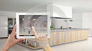 Smart remote home control system on a digital tablet. Device with app icons. Interior of professional modern wooden kitchen