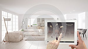 Smart remote home control system on a digital tablet. Device with app icons. Interior of scandinavian white living room and kitche