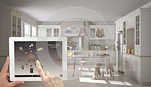 Smart remote home control system on a digital tablet. Device with app icons. Interior of scandinavian white and wooden kitchen in