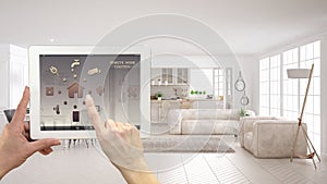 Smart remote home control system on a digital tablet. Device with app icons. Modern scandinavian living room with sofa and kitchen