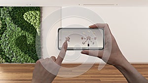 Smart remote home control system on a smart phone. Device with app icons. Interior of empty room with vertical garden in the