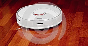 Smart robot vacuum cleaner with lidar on wood floor. Robot vacuum cleaner performs automatic cleaning of the apartment. 4K