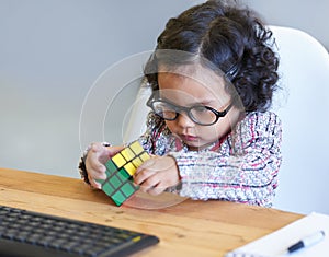 Smart, rubix cube and a child for playing, learning and strategy with color at a desk. House, clever and a girl, young photo