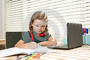 Smart school boy does homework in school class. Writes text from laptop notebook.