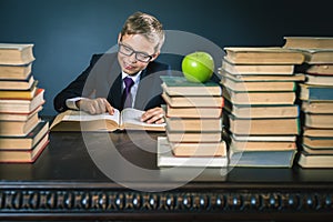 Smart school boy reading a book at library