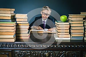 Smart school boy reading a book at library