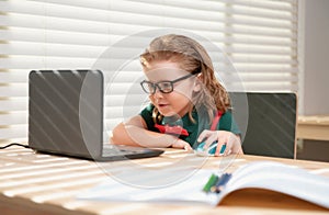 Smart school boy writing homework using notebook computer to study. Little student, schoolboy learning online.