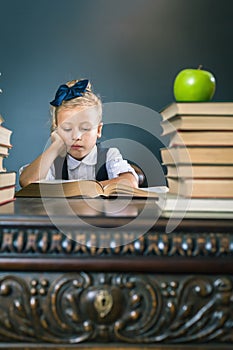 Smart school girl reading a book at library