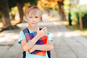 Smart schoolboy holding books outdoors. Education and elementary school. Little student with schoolbag