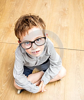 Smart schoolboy with oversized eyeglasses looking up - high angle view