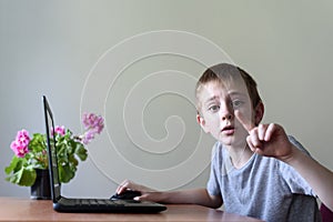 Smart schoolboy sitting at a laptop and explains something. Home education