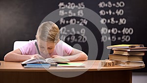 Smart schoolboy solving task, math exercises written on blackboard behind