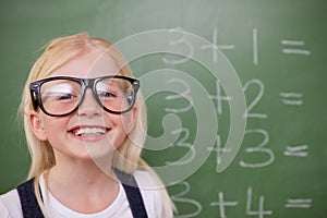 Smart schoolgirl posing in front of a blackboard
