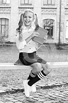 Smart schoolgirl. Student adorable child in formal uniform relaxing outdoors. Schoolgirl reading book. Little genius