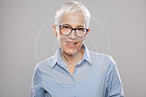 Smart senior businesswoman with glasses in a blue shirt and gray white hair and glasses