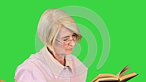 Smart senior woman reading a book emotionally on a Green Screen, Chroma Key.