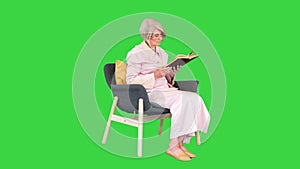 Smart senior woman reading a book emotionally on a Green Screen, Chroma Key.