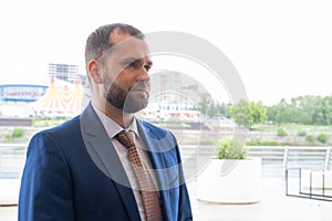 A smart, serious, confident man in a business suit against a blurry urban landscape. Portrait of a middle-aged