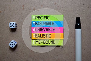 SMART - Specific, Measurable, Achievable, Realistic, And Time-Bound write on Sticky note. Isolated on wooden table photo