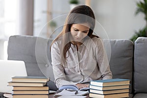 Smart student preparing for test exam reading textbook at home