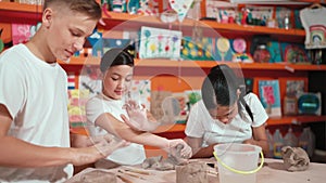 Smart student using hand press on clay piece at pottery workshop. Edification