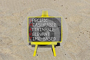 SMART symbol. Concept words SMART specific measurable attainable relevant time-based on blackboard. Beautiful sand background