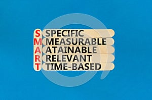 SMART symbol. Concept words SMART specific measurable attainable relevant time-based on stick. Beautiful blue background. Business