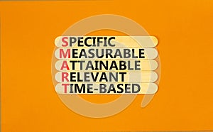 SMART symbol. Concept words SMART specific measurable attainable relevant time-based on stick. Beautiful orange background.
