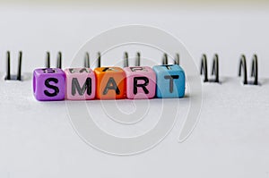 SMART text on colorful plastic beads representing Specific, Measurable, Achievable, Relevant and Time Bound with notepad photo