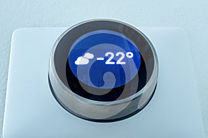 A Smart thermostat showing the outside weather temperature at night during winter