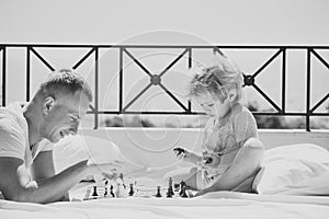 Smart toddler concept. Parent play chess with kid on terrace on sunny day. Kids playing with toys. Dad with child play