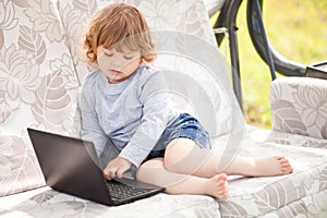 Smart toddler girl using laptop computer, child and technology.