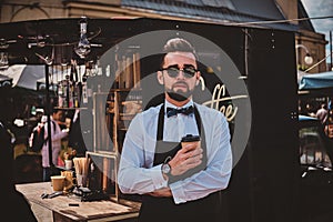 Smart trendy barista in glasses has a break at his own coffeeshop.