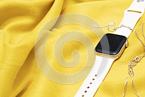 Smart watch on a colorful background and gold items. New smart pink watch on yellow background, copy space.