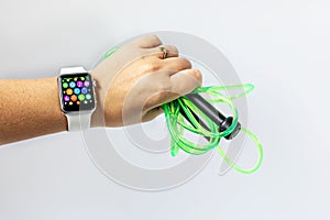 Smart watch during fitness. In a female hand a sports skipping rope on a white background. Physical activity monitoring