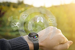 Smart watch, fitness tracker on hand in the outdoor on a blurred green background with icons of basic functions.Concept of The