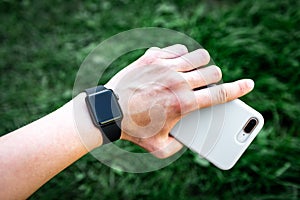 Smart watch and mobile phone on grass background