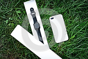 Smart watch and mobile phone on grass background