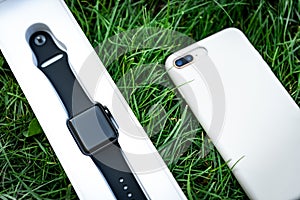 Smart watch and mobile phone on grass background