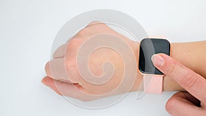 Smart watch with a pink strap on a woman`s hand on a white background