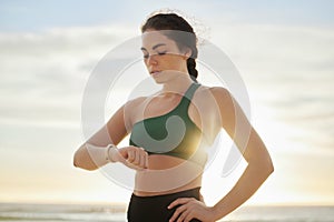 Smart watch, woman and fitness at sunset on beach for exercise workout, training and nature. Stopwatch, sports and