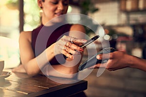 The smart way to pay. Closeup shot of a woman paying using NFC technology in a cafe.