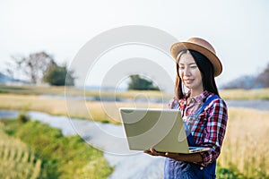 Smart Woman farmer looking barley field with laptop