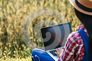 Smart Woman farmer looking barley field with laptop