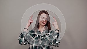 Smart woman with glasses thinks, holds index fingers at temple of the head